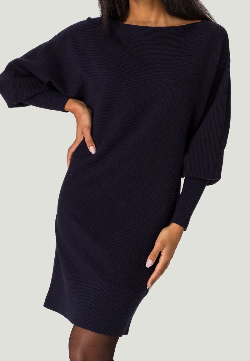 Abito lavorato a maglia blu navy con una vestibilità ampia, scollatura a barca larga e maniche lunghe. Presenta una texture a coste e orlo, offrendo un aspetto accogliente.