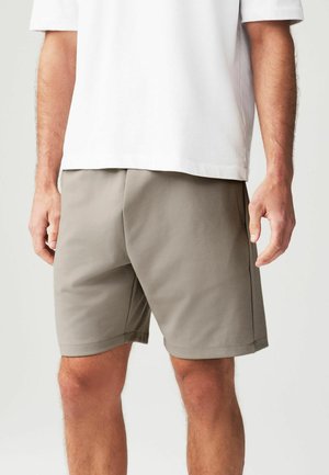 Graue Shorts aus glattem, leichtem Stoff, mit geradem Schnitt, Seitentaschen und elastischem Bund. Getragen mit einem weißen T-Shirt.