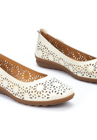 Bailarinas de cuero crema con patrones de flores recortados, plantillas acolchadas marrones y suela de goma flexible. Diseño de punta redondeada.