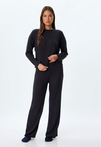 Marineblauw ribbed loungewear-set met lange mouwen, een ronde hals en losse broek met een elastische tailleband. Gladde stoftextuur.