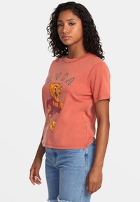 Camiseta corta color coral hecha de un tejido suave, con un gráfico audaz de un tigre en colores vibrantes y el texto "RVCA" encima.