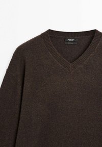 Brun kashmirtröja med V-ringning, ribbad halsringning och långa ärmar med en mjuk, texturerad finish.