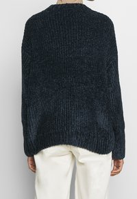 Granatowy sweter z prążkowanego dzianiny z długimi rękawami, szerokim dekoltem i luźnym krojem. Teksturowana tkanina o lekko oversize'owej sylwetce.