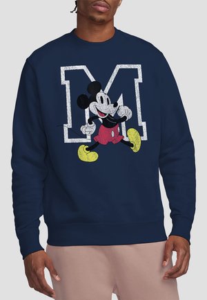 Dunkelblaues Sweatshirt mit einem großen strukturierten Buchstaben "M" und einer Grafik von Mickey Mouse in roten Shorts und gelben Schuhen.