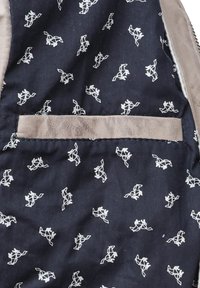 Marinblå tyginteriör med vita abstrakta hästmönster. Inkluderar en läderdetaljerad ficka sydd i designen. Mjuk textur.