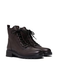 Brązowe skórzane botki za kostkę o gładkim wykończeniu, okrągłym nosku, sznurowaniu z przodu i solidnej czarnej gumowej podeszwie. Obecne są subtelne detale przeszyć.