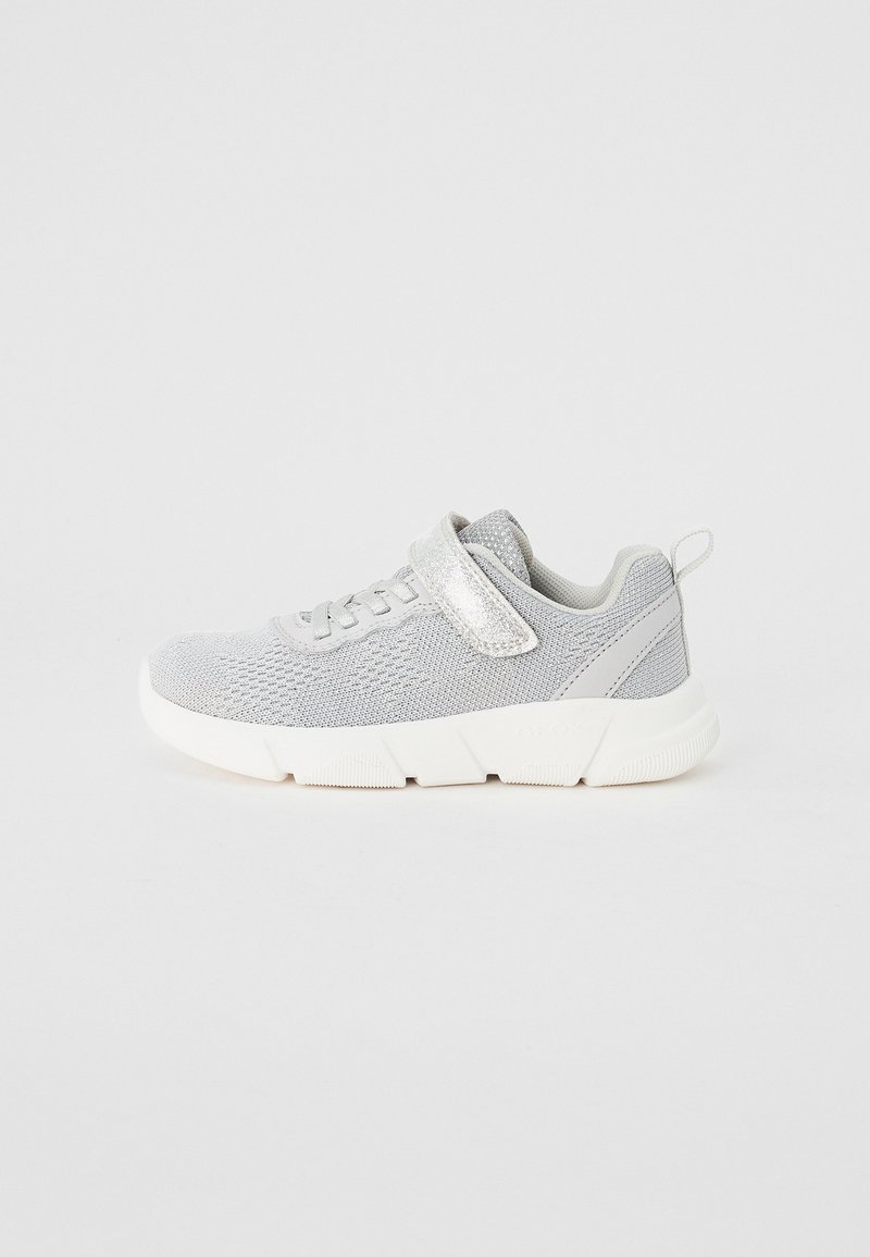 Grey knit sneakers feature a textured upper, a secure velcro strap, and a white rubber sole with grooved detailing for traction.