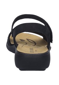 Zwarte sandaal met twee zachte banden en een gevoerde beige voetbed. Heeft een gevormde zool en getextureerde accenten.