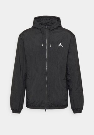 Czarna kurtka z kapturem i zamkiem błyskawicznym, elastycznymi mankietami i małym białym logo Jumpman na lewej piersi.