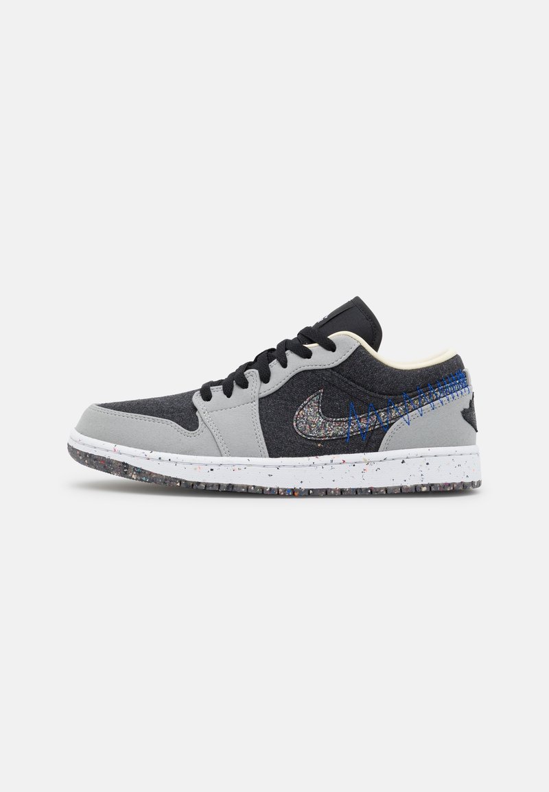 Baskets basses en tissu noir et gris, lacets noirs, semelle tachetée et swoosh Nike multicolore texturé avec détails de couture bleue.