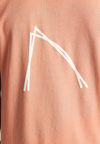 Felpa rosa con un design astratto bianco sulla parte anteriore, caratterizzata da linee texture sullo sfondo in tessuto.
