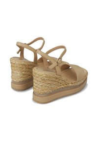 Sandalias de cuña beige con talón de yute trenzado, que cuentan con correas ajustables y un acabado brillante en la parte superior de cuero.