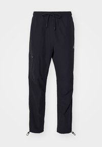 Schwarze schmal geschnittene Hose mit elastischem Bund und Kordelzug, seitlicher Reißverschluss-Tasche und verstellbaren Fußbündchen.