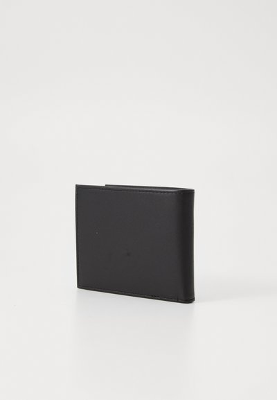 Portefeuille en cuir noir avec une texture lisse et un design minimaliste. Il présente une forme pliée et des coutures visibles le long des bords.