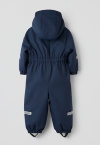 Marineblauwe geïsoleerde jumpsuit met capuchon, elastische tailleband en elastische manchetten. Voorzien van reflecterende accenten op de armen en benen. Gladde textuur.