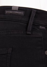 Svarta denimjeans med en läderlapp märkt "CITIZENS of HUMANITY", med ton-i-ton-sömnad och en sidoficka.