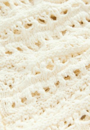 Tessuto bianco lavorato a maglia con un motivo a traforo, caratterizzato da anelli e punti texturizzati, creando un aspetto delicato e arioso.