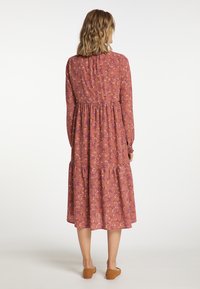 Rochie cu mâneci lungi, până la genunchi, în nuanță de roz prăfuit, cu un model floral, talie strânsă și fustă în straturi. Țesătură moale, ușoară.