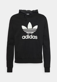 Fekete kapucnis dzseki sima textúrájú anyagból, fehér Adidas logóval és ikonikus háromcsíkos mintával a mellkason.