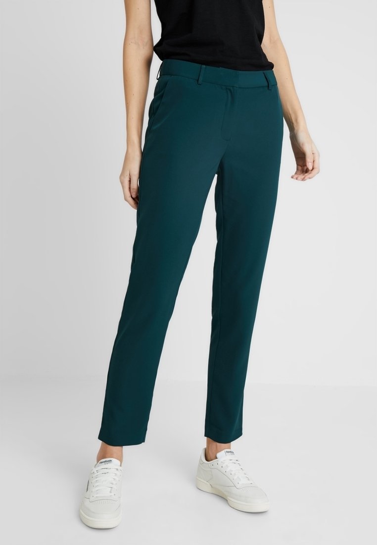 Tealfärgade skräddarsydda byxor med rak passform, tillverkade av ett slätt material. Har en midja med bältesöglor och sidofickor.