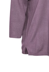 Lila t-shirt med korta ärmar, tillverkad av ribbat stickat material. Har sidoklipp vid fållen för ökad rörelsefrihet.