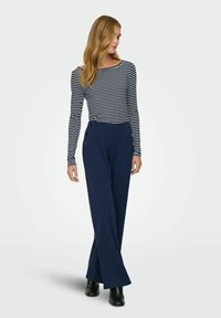 Striped long-sleeve top in navy and white, paired with high-waisted, wide-leg navy pants featuring gold button accents. Smooth fabric texture.