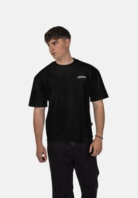 Černé tričko s krátkým rukávem a volným střihem. Na hrudi se nachází malé bílé logo "CRYSTAL". Měkký materiál a jednoduchý design.