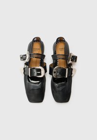 Schwarze Lacklederschuhe mit quadratischen Zehen, zwei verstellbaren Schnallen und strukturierten Akzenten. Das Innere ist mit einem braunen Futter und Markenlogo ausgestattet.