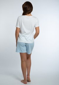 Valkoinen puuvillapaita, jossa on lyhyet hihat, yhdistetty sinivalkoisiin raidallisiin shortsihin. Ominaisuuksiin kuuluu rento istuvuus ja pehmeä tekstuuri.