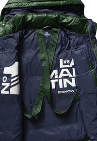 Navy blue puffer jacket interior, featuring a green, quilted lining and bold white text "LA MARTINA" with accents; metal snaps visible.