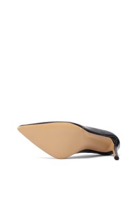 Chaussure à talon haut en cuir verni noir, couchée sur le côté, montrant une semelle beige lisse et un bout pointu avec un talon fin sur fond blanc.