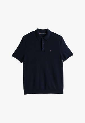 Polo de manga corta azul marino con tapeta de dos botones y pequeño logotipo rojo, blanco y azul en el lado izquierdo del pecho.