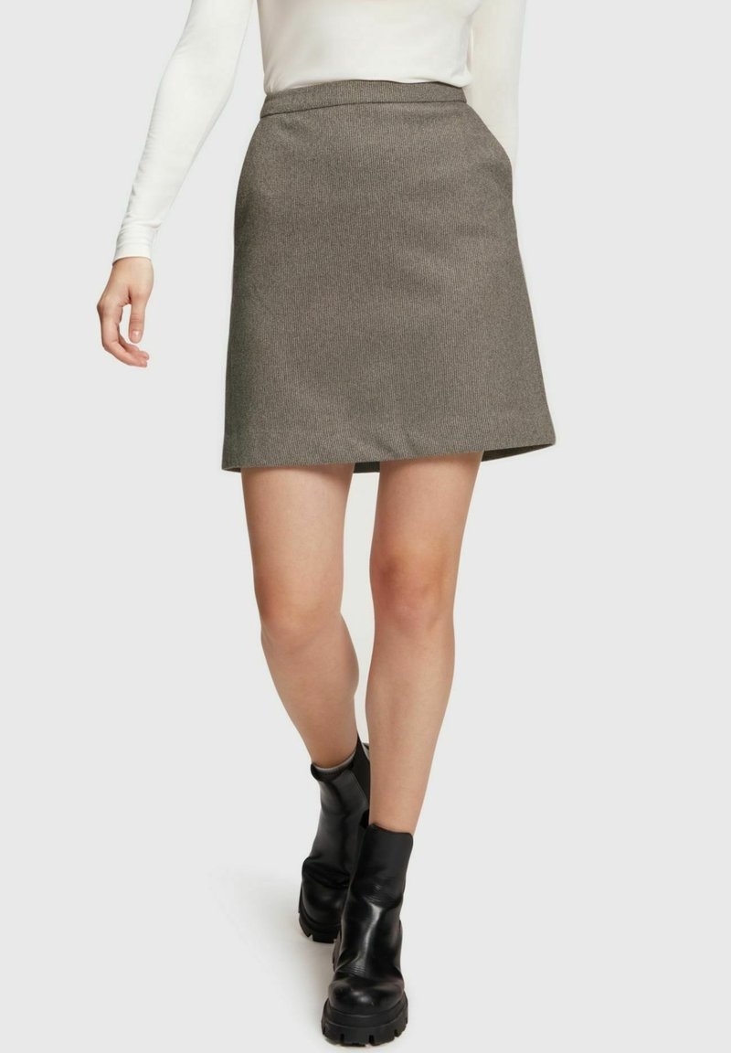 Grå knä-lång a-linje kjol i texturerad tyg, med hög midja och en ren fåll, ihop med svarta anklar stövlar.