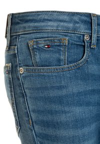 Blå denimjeans i standard passform, med synliga sömmar, en liten logotyp på bakfickan och en metallknapp som stängning.