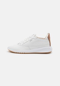 Zapatillas deportivas blancas con una parte superior texturizada que presenta perforaciones, una suela lisa y un acento de cuero marrón en el talón.