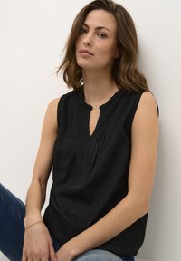 Top senza maniche nero con un design plissettato, scollatura rotonda e un piccolo taglio a forma di chiave sul davanti. Tessuto morbido e testurizzato.