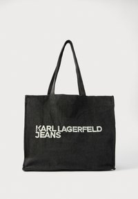 Fekete vászontáska hosszú fogantyúkkal, az elején vastag fehér felirattal: „KARL LAGERFELD JEANS”. Egyszerű, téglalap alakú kialakítás.