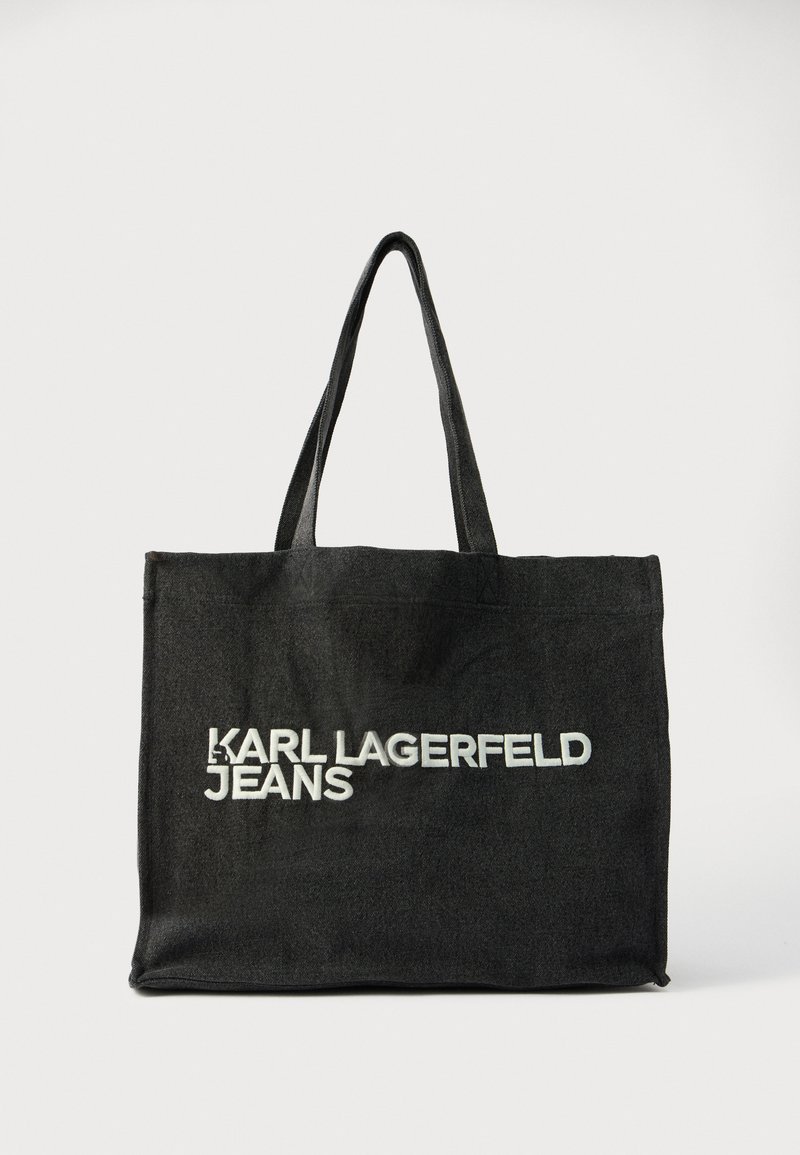 Fekete vászontáska hosszú fogantyúkkal, az elején vastag fehér felirattal: „KARL LAGERFELD JEANS”. Egyszerű, téglalap alakú kialakítás.