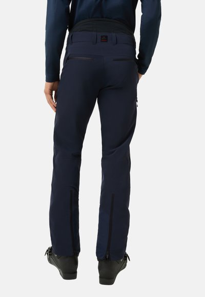 Pantalons de ski imperméables navy avec coupe ajustée, dotés de poches zippées, de coutures renforcées et de zips aux chevilles pour un enfilage facile et une ventilation.