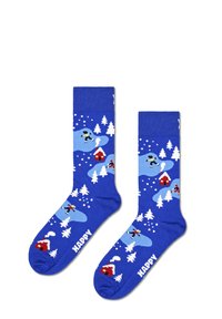 Calcetines azules con patrones blancos de nieve, árboles y patinadores, con casas rojas y la palabra "HAPPY" en blanco en la punta.