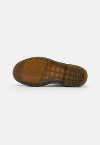 Suela de zapato de goma con una superficie marrón texturizada, con estrías y un diseño de agarre estampado, adecuado para una mejor tracción.