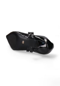 Chaussure en cuir verni noir avec un bout pointu, deux fines sangles et une semelle plate, ornée d'un petit accent doré sur le côté.