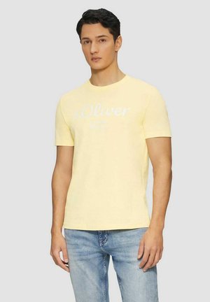 Yellow cotton t-shirt with a crew neck and short sleeves. Features white logo print on the front, paired with blue denim jeans.