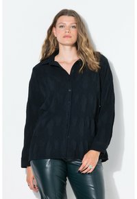 Camicia nera con bottoni a maniche lunghe e colletto, caratterizzata da un motivo testurizzato. Combinata con pantaloni in pelle verde. Design semplice senza loghi visibili.