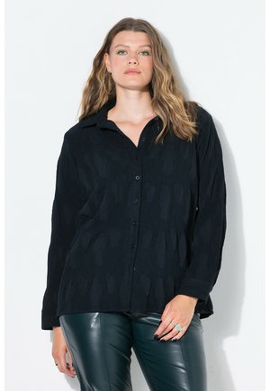 Chemise noire à boutons avec un motif texturé, à manches longues et col classique. Assortie à un pantalon en cuir vert. Design simple sans logos visibles.