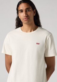 Lichtcrème T-shirt met korte mouwen en subtiele textuurstrepen. Heeft een klein rood Levi's-logo op de linkerborst.