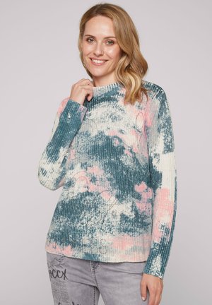 Pull à côtes présentant un mélange de couleurs teal, rose et crème avec un design texturé. Encolure haute et manches longues.