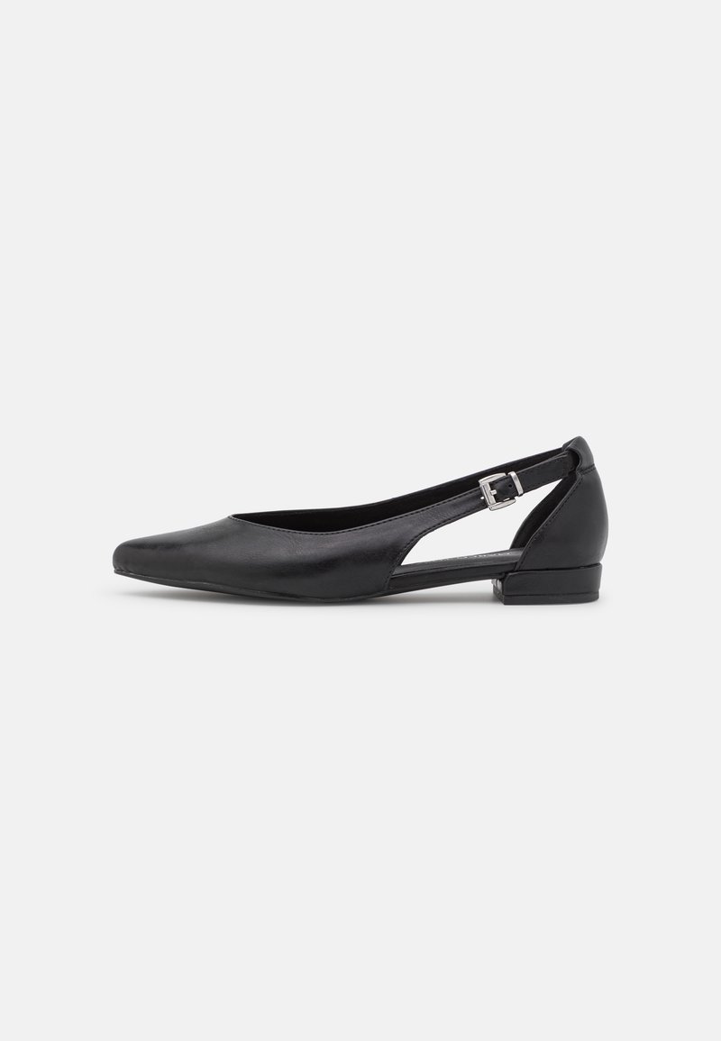 Chaussure plate en cuir noir avec bout pointu, talon bas et bride autour de la cheville avec boucle argentée, présentée sur fond blanc.