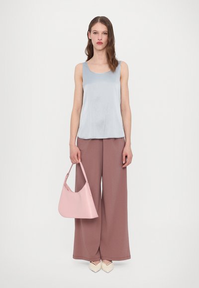 Top senza maniche di un blu chiaro, pantaloni larghi color blush e borsa rosa. Il tessuto sembra morbido con texture lisce, e le scarpe sono di color avorio.