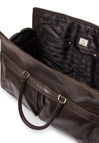 Attaché en cuir brun foncé avec deux poignées, fermeture éclair en haut, intérieur doublé de tissu noir à motifs avec des poches et des pressions en métal.